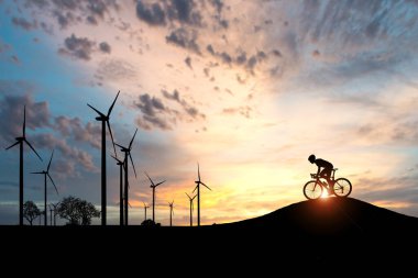 Dünyayı ve çevreyi kurtarmak için temiz enerji kavramı. Rüzgar jeneratörleri ve bisikletçiler