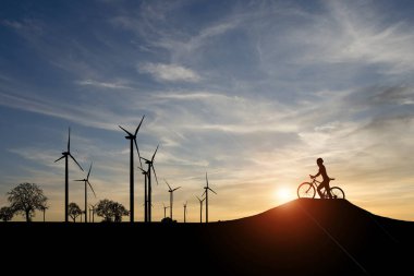 Dünyayı ve çevreyi kurtarmak için temiz enerji kavramı. Rüzgar jeneratörleri ve bisikletçiler