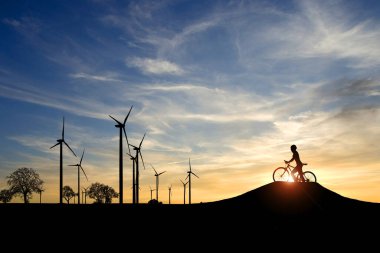 Dünyayı ve çevreyi kurtarmak için temiz enerji kavramı. Rüzgar jeneratörleri ve bisikletçiler