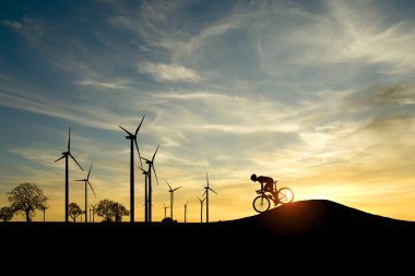 Dünyayı ve çevreyi kurtarmak için temiz enerji kavramı. Rüzgar jeneratörleri ve bisikletçiler