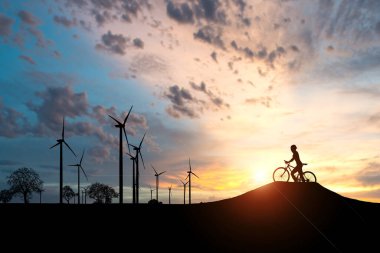 Dünyayı ve çevreyi kurtarmak için temiz enerji kavramı. Rüzgar jeneratörleri ve bisikletçiler