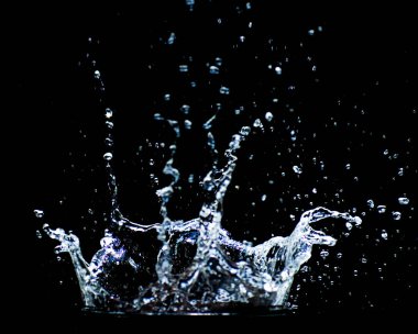 Su siyah bir zemine saçılmış. Siyah arka planda su sıçraması. Siyah arkaplanda izole sıçrama