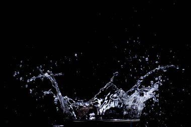 Su siyah bir zemine saçılmış. Siyah arka planda su sıçraması. Siyah arkaplanda izole sıçrama