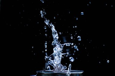 Su siyah bir zemine saçılmış. Siyah arka planda su sıçraması. Siyah arkaplanda izole sıçrama