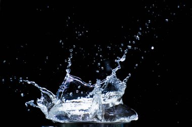 Su siyah bir zemine saçılmış. Siyah arka planda su sıçraması. Siyah arkaplanda izole sıçrama