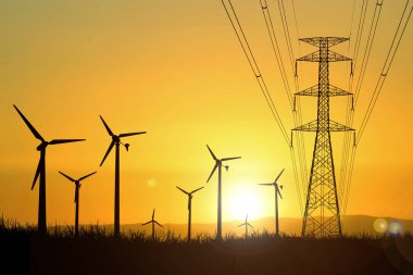 Rüzgar türbininin siluetleri akşam saatlerinde tarlalarda elektrik üretmek için kullanılır..