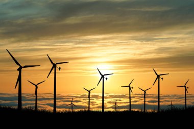 Rüzgar türbini elektrik üretmek için kullanılır. Yenilenebilir Enerji Konseptleri ve Dünya Enerji Tasarruf Edin. Gün batımında rüzgar santralinin silueti