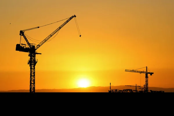 Silhouette of a crane in a construction site. Crane concept for the construction industry