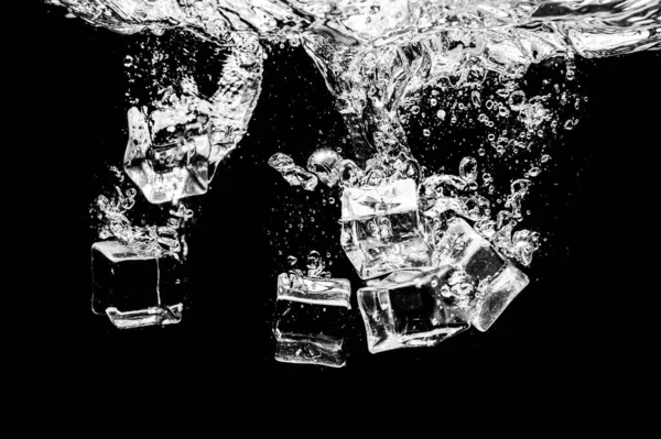 Ice cubes in water on studio dark background. The concept of freshness with coolness from ice cubes.