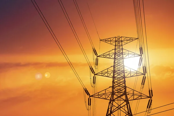 Silhouette of high voltage poles with electric wires. Silhouette of high voltage power line cables in an orange evening sunset. Steel structure of electric poles. electric power transmission concept