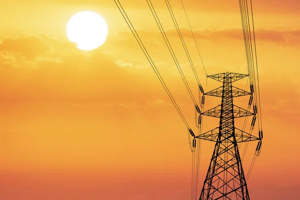 Silhouette of high voltage poles with electric wires. Silhouette of high voltage power line cables in an orange evening sunset. Steel structure of electric poles. electric power transmission concept