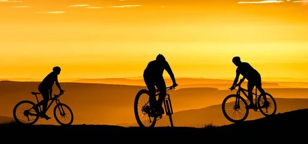 Silhouette of a mountain bikers enjoying downhill during the sunset. Mountain bike concept. Mountain bike race - silhouette cyclist on background.