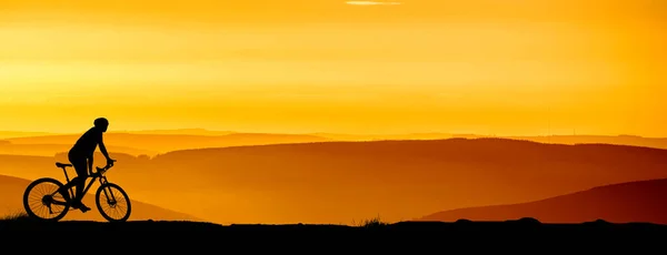 Silhouette of a mountain bikers enjoying downhill during the sunset. Mountain bike concept. Mountain bike race - silhouette cyclist on background.