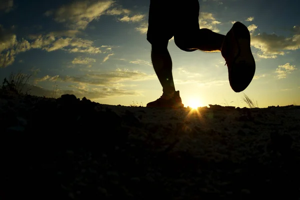 Silhouette of runner practicing running on the mountains In the evening With a backdrop of the sun
