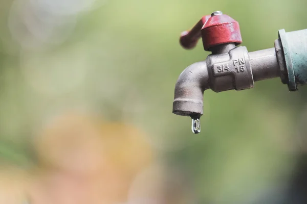 Concept of wasting water, not saving water. Water tap with dripping water when closed