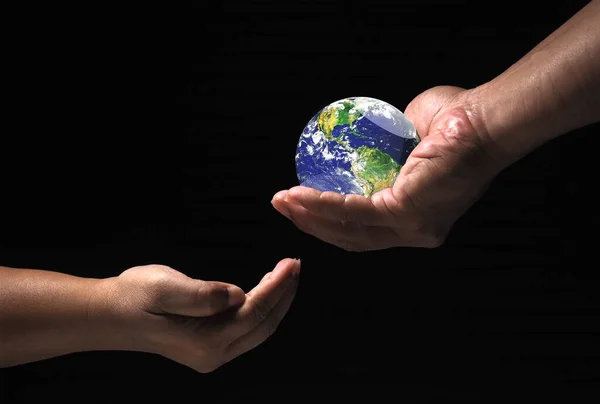 environmental protection concept The world for the future. globe in hand passed to the other on black background