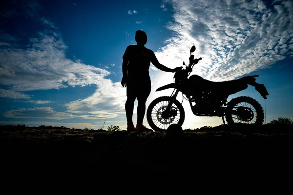 Silhouette Man enjoying a motocross bike on a beautiful evening in the mountains.