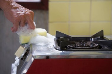 Sünger mutfak temizlik malzemesi kullanan erkek eli gaz fırını fırçası, seçici odaklanma                               