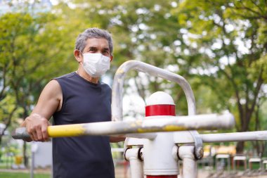 Koruma maskeli yaşlı bir adam halka açık parkta spor yapıyor, yaşlılarda konsept sağlık hizmetleri, yaşam tarzı.    