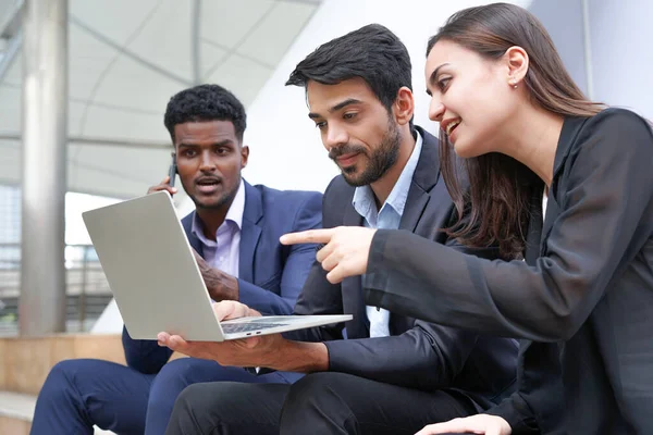 young confidence business teamwork sitting and working on laptop outside building                                 