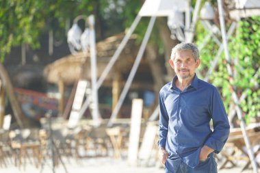 Tropikal bir adada gelişigüzel duran kıdemli iş adamı.                       