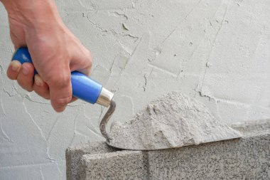 Endüstriyel tuğla ustasının elinde alüminyum mala havan topu bir tuğla bloğu, yeni beton duvarın arka plan deseni ve metin için kopyalama alanı var..