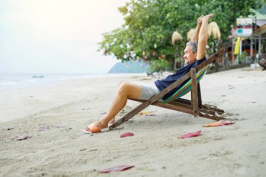 Sahilde plaj sandalyesinde uzanan son sınıf öğrencisi, rahatlatıcı, dinlenen, seyahat eden, tatil, yaşam tarzı, yaşam kalitesi vb.                               