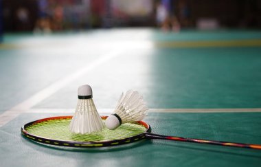 Yeni ve kullanılmış badminton sahası zeminine raket konuldu. Mekik siki seçici bir odak noktası.                                                                                          