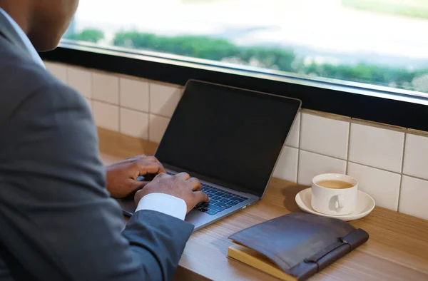 african american businessman typing laptop while working at counter bar in cafe indoor ,selective focus at his hands