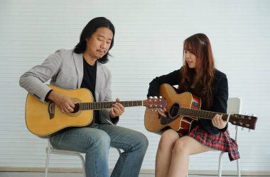 Müzik akademisi stüdyo sınıfında gitar çalan öğretmen ve öğrenci bir öğrenciye seçici bir şekilde odaklanırlar. Müzisyen yaşam tarzı, müzik eğitimi akademisi konsepti