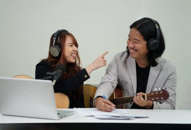 İkili sanatçılar laptopta fan kulübüyle canlı müzik radyosunda sohbet ederken keyifle sohbet ediyorlar.