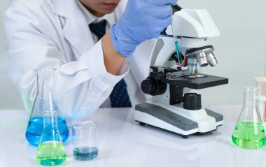 Kimya laboratuvarında çalışan bilim adamı mikroskopla kimya deneyleri yapıyor.