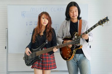 Akademi müzik sınıfında gitar çalan bir kız ve öğretmen. Müzik sınıfında iki müzisyen gibi şakacı.