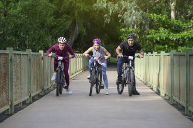 group of young friends ride bicycle on weekend, happy people cycling on walkway in the park