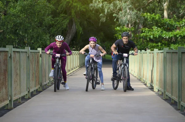 group of young friends ride bicycle on weekend, happy people cycling on walkway in the park