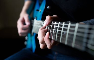 Gitar çalan gitarist, arka planda oturan ve elektro gitar çalan bir adam.
