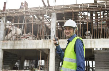 İnşaat alanındaki işçilerle telsiz iletişimi kullanan kıdemli mühendis.