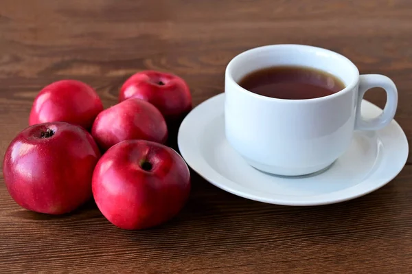 木製のテーブルとお茶の白いカップに横たわっている赤いリンゴの秋の組成物 家庭の快適さと暖かさの概念 こんにちは — ストック写真