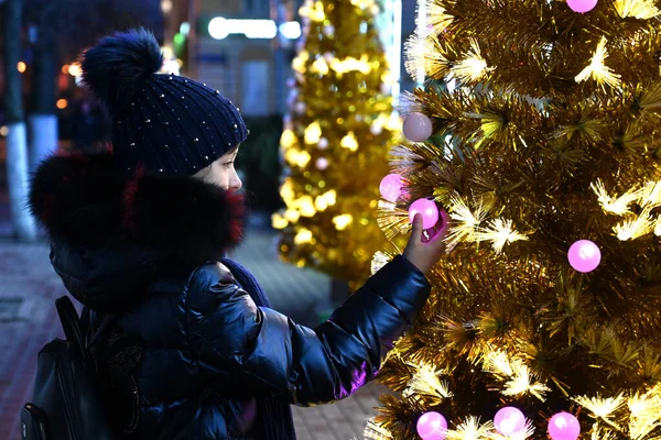 Ένα Κορίτσι Κοιτάζει Ένα Όμορφο Τεχνητό Χριστουγεννιάτικο Δέντρο Στην Πόλη — Φωτογραφία Αρχείου