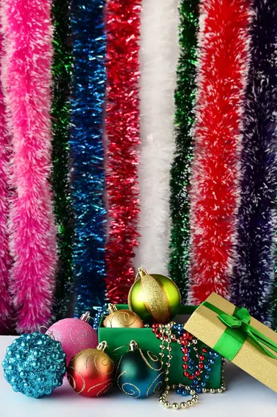 美しいクリスマスの装飾 おもちゃ ビーズ 前景の箱のボール バックにはギフトバッグとマルチカラーのティネルがあります 新年の準備 — ストック写真
