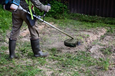 Bahçıvan çim biçme makinesiyle çim biçer. Tıraş makinesi insanın elinde. Bahçe işleri kavramı. Bahçe bakımı