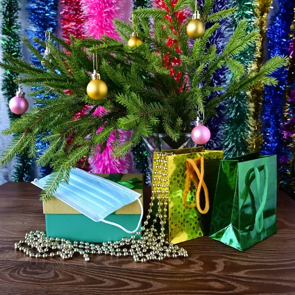 クリスマスツリーの下で美しいパッケージの贈り物 上は使い捨て医療用マスク 隔離中の大晦日だ 感染やウイルスからの保護 — ストック写真