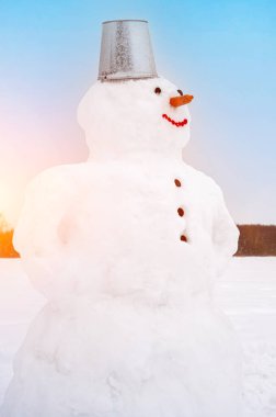 Tarlada karla kaplı sevimli gülümseyen kardan adam. Sanatsal olarak renkli ve renkli fotoğrafçılık