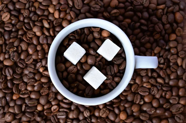 Biały Kubek Ziarnem Kawy Trzema Kawałkami Cukru Tle Kawy Zbliżenie — Zdjęcie stockowe