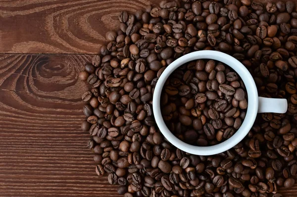 コーヒー豆の入った白いカップ 木製のテーブルの上にコーヒー豆 トップビューのフラットレイアウト スペースのコピー — ストック写真