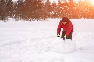 Bir adam bir kardan adam için kartopu yapar. Sanatsal olarak renkli ve renkli fotoğrafçılık