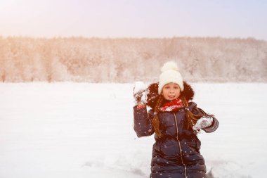 Güzel mutlu kız kartopu oynuyor, gülüyor ve karla eğleniyor. Sanatsal olarak renkli ve tonlu fotoğraf