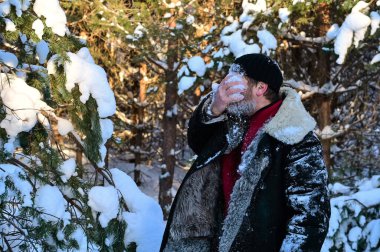 Sakallı vahşi bir adam ormanda yüzünü karla yıkar. İnsan zor koşullarda hayatta kalır, dayanıklılık ve sertleştirme. Kış Macerası