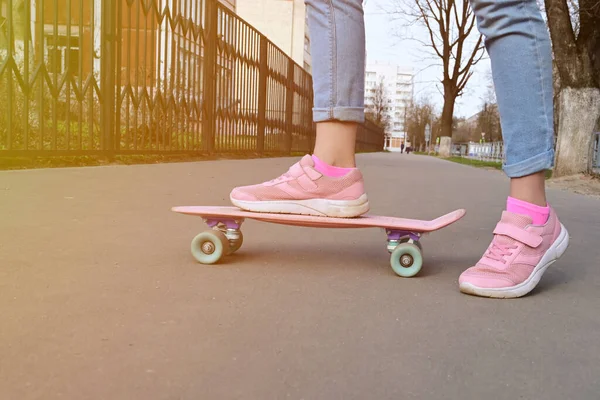 ピンクのペニースケートロングボードに乗ってクローズアップ足の女の子のスケートボーダーブルージーンズとピンクのスニーカー スポーツと開発の概念 芸術的なトーンと着色 選択的フォーカス — ストック写真