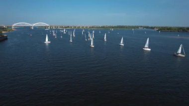 Yat yarışları. Nehirde çok sayıda gemi seyrediyor. Şafak söküyor. Yat yarışı.